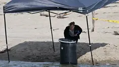 Seorang pejabat berdiri di samping tong tempat mayat ditemukan di Malibu Lagoon State Beach, California pada 31 Juli 2023.(AFP/Robyn Beck)