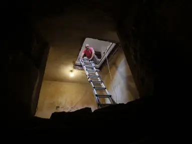 Tal menurunkan tangga ke lorong yang terdapat kolam ritual Yahudi (Mikveh) yang ditemukan di rumahnya, Ein Karem, Yerusalem (1/7/2015). Tal menemukan Mikveh yang diyakini berusia lebih dari 2.000 tahun saat sedang merenovasi rumah.  (AFP/GALI TIBBON)