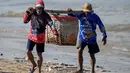 Sementara, perdagangan ikan di Bali berpusat pada perikanan tangkap (tuna, kakap) dan budidaya, dengan pelabuhan utama di Benoa, Kedonganan, dan Pengambengan. Tampak dalam foto, para pekerja membawa ikan setelah para nelayan menurunkan hasil tangkapan mereka dari perahu di pantai Kedonganan dekat Denpasar, Bali, pada Jumat 10 April 2026. (SONNY TUMBELAKA/AFP)