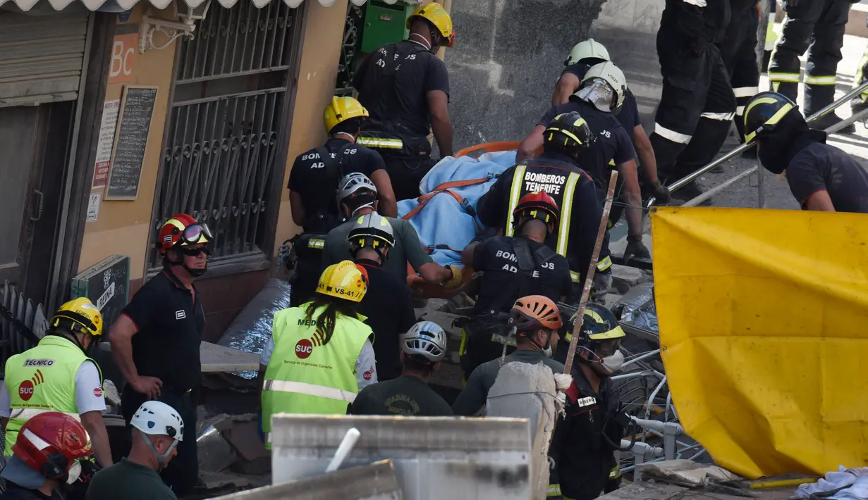 Petugas mengevakusi jenazah korban runtuhnya gedung apartemen lima lantai di kota wisata Los Cristianos, Tenerife, Spanyol, Kamis (14/4). Sedikitnya satu orang tewas dan sembilan lainnya terjebak di dalam reruntuhan gedung tersebut. (Desiree MARTIN/AFP)