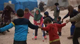 Bocah Suriah, Maya Merhi bermain bersama teman-temannya di kamp Serjilla, 9 Desember 2018. Sebelumnya, gadis 8 tahun yang lahir tanpa kaki karena kondisi bawaan terpaksa menggunakan kaki palsu dari kaleng ciptaan sang ayah. (Aaref WATAD/AFP)