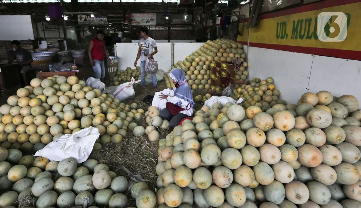 Aktivitas pedagang buah di salah satu kios Pasar Induk Kramat Jati, Jakarta Timur, Minggu (12/4/2020). Kegiatan di pasar tersebut berjalan normal selama pandemi COVID-19, namun penjual dan pekerja masih terlihat belum mengenakan masker. (Liputan6.com/Johan Tallo)