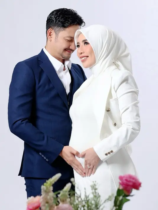 Di pemotretan kali ini, Angga tampak mengenakan setelan kemeja biru. Sementara itu, sang istri tampil dengan balutan serba putih, serasi dengan warna kemeja yang dipakai suami. Paras cantik Nurul Kamaria dengan baby bump yang semakin besar pun curi perhatian warganet. (Liputan6.com/IG/@anggawijaya88)