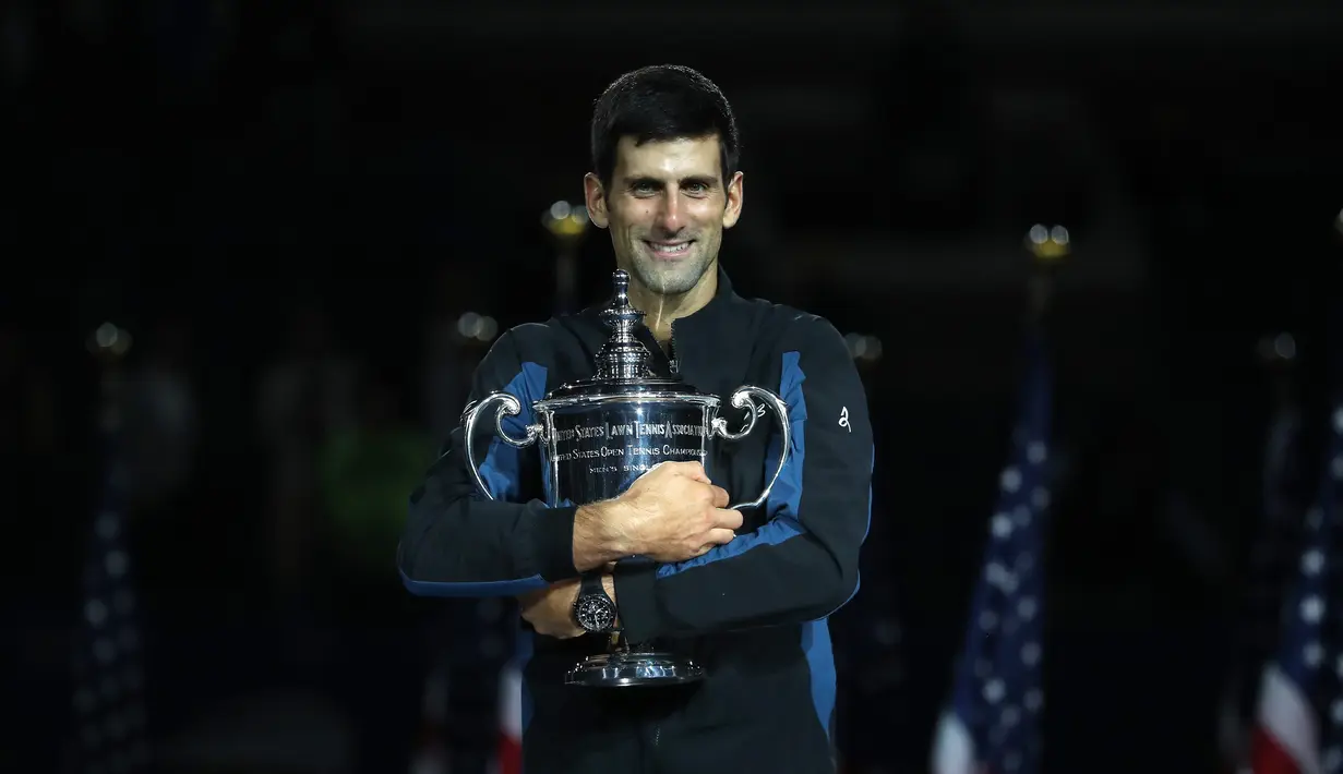 Petenis Serbia, Novak Djokovic memegang trofi AS Terbuka setelah mengalahkan Juan Martin del Potro pada partai final di New York, Minggu (9/9). Gelar ini adalah yang keempat di AS Terbuka sejak yang terakhir pada 2015. (MATTHEW STOCKMAN/GETTY IMAGES/ AFP)