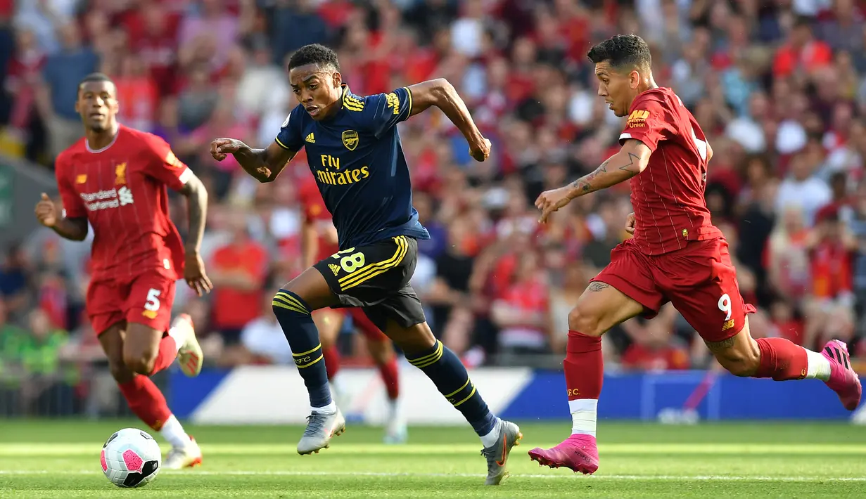 Gelandang Arsenal Joe Willock (tengah) menggiring bola melewati pemain Liverpool Roberto Firmino (kanan) saat bertanding dalam Liga Inggris di Stadion Anfield, Liverpool, Inggris, Sabtu (24/8/2019). Liverpool menang 3-1 dan kukuh di puncak klasemen sementara. (BEN STANSALL/AFP)