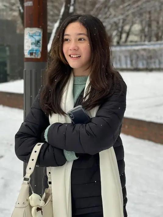 Menikmati salju Korea, Mikhaela memilih mengenakan padding jaket hitam, dipadukan syal putih dan inner sweater hijau mint.  [@nafaurbach]