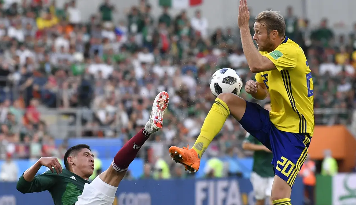 Pemain Meksiko, Edson Alvarez (kiri) menghalau bola dari kejaran pemain Swedia, Ola Toivonen pada laga grup F Piala Dunia 2018 di Yekaterinburg Arena, Yekaterinburg, Rusia, (27/6/2018).  Swedia menang telak 3-0 atas Meksiko. (AP/Martin Meissner)