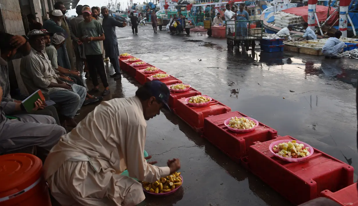 Seorang nelayan menyiapkan makanan berbuka puasa selama bulan suci Ramadhan di galangan kapal di kota pelabuhan Karachi Pakistan pada 18 April 2022. Setelah menjalani ibadah puasa, waktu buka puasa menjadi momen yang dinanti oleh umat Islam. (Rizwan TABASSUM / AFP)