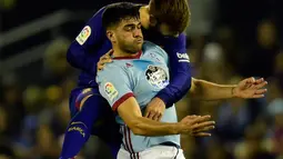 Pemain Barcelona, Gerard Pique berebut bola dengan pemain Celta Vigo, Maxi Gomez pada pertandingan leg pertama babak 16 besar Copa del Rey di Stadion Balaidos, Kamis (4/1). Barcelona harus puas bermain imbang  dengan skor 1-1. (MIGUEL RIOPA/AFP)