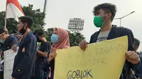 Puluhan mahasiswa membentuk barisan sambil membentangkan poster satire yang ditujukan untuk anggota DPR dalam demo tolak Omnibus Law. (Liputan6.com/Ady Anugrahadi)