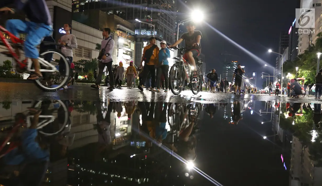 Warga menikmati car free night saat malam pergantian tahun di Jalan MH Thamrin, Jakarta, Senin (31/12). Hujan yang mengguyur Jakarta sejak siang tidak menyurutkan antusias warga menikmati car free night. (Liputan6.com/Angga Yuniar)