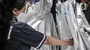 Pekerja menunjukkan berbagai jenis baju hazmat yang dijual di salah satu industri konveksi Pusat Industri Kecil (PIK), Jakarta, Rabu (30/12/2020). Dalam sehari, industri konveksi di PIK mampu memproduksi 50 buah baju hazmat tiap pekerja. (merdeka.com/Iqbal S. Nugroho)