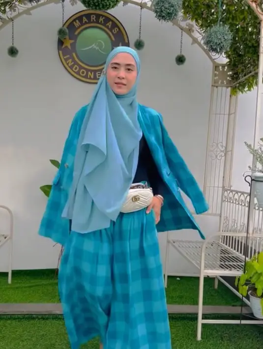 Ia juga tampil dengan setelan warna biru kotak-kotak dari blazer dan celana pallazonya, dipadukan kerudung biru dan tas pinggang Gucci putih. [@apriljasmine]
