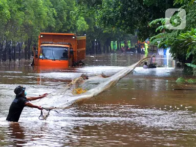 Warga menjala ikan di tengah jalan yang tertutup banjir di kawasan TB Simatupang, Jakarta Selatan, Sabtu (20/2/2021). Banjir terjadi akibat luapan Kali Serua yang berada di pinggir jalan tol. (merdeka.com/Arie Basuki)