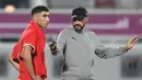 Bek Maroko, Achraf Hakimi mendengarkan pelatih Walid Reragui selama sesi latihan jelang menghadapi Prancsi di babak semifinal Piala Dunia 2022  di Stadion Al Duhail SC di Doha pada 13 Desember 2022. Maroko berhasil lolos ke semifinal usai menyingkirkan Portugal dengan skor 1-0 pada babak perempat final. (AFP/Karim Jaafar)