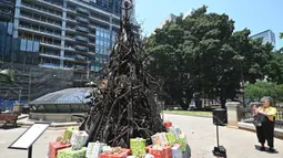 Seorang wanita megambil foto instalasi yang dijuluki 'Pohon Natal yang Terbakar' di Sydney (18/12/2019). Instalasi Pohon Natal ini untuk mendukung Dana Bantuan dan Pemulihan Bencana Palang Merah Australia di tengah situasi kebakaran hutan. (AFP/Peter Parks)
