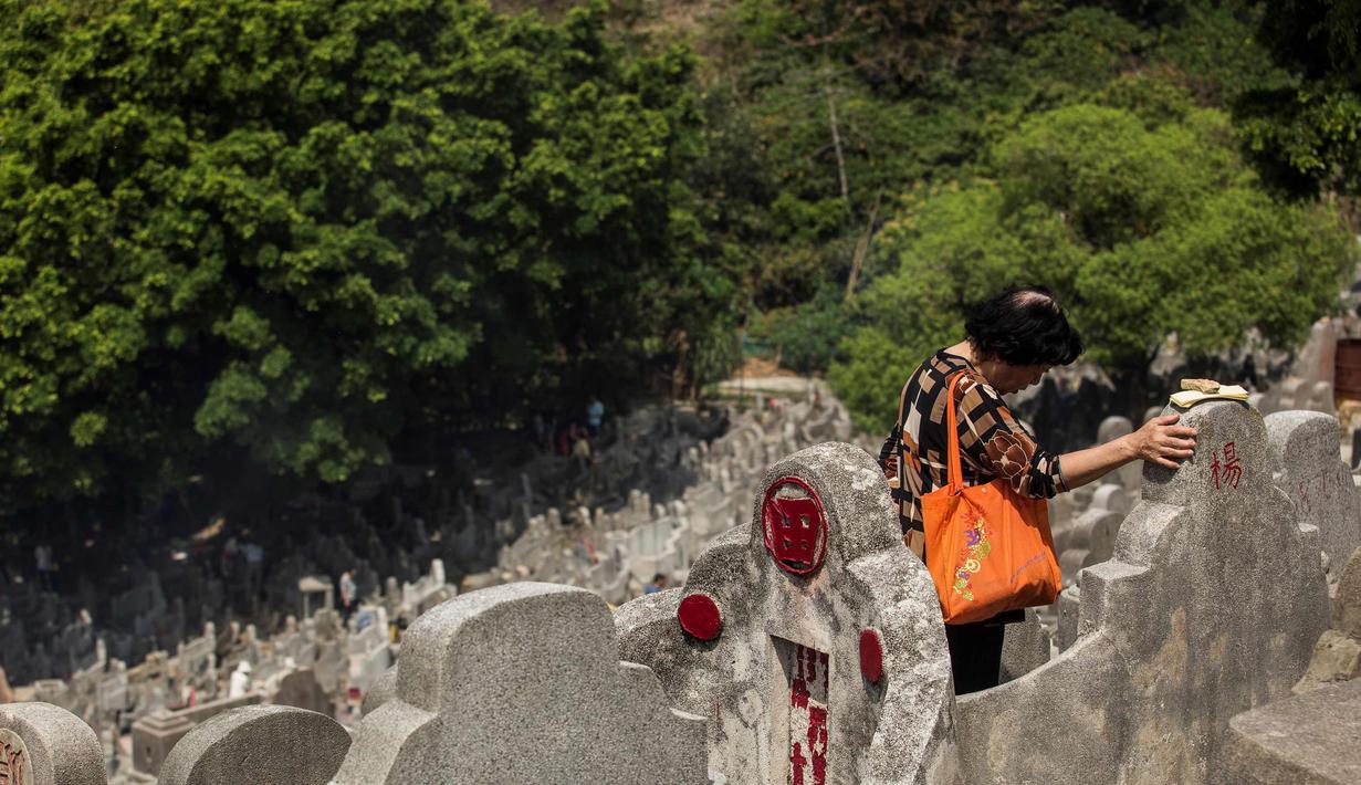 Soerang wanita berdoa di makam kerabat selama festival Qingming di pemakaman di Hong Kong (5/4). Festival Qingming atau dikenal sebagai Hari Pembersihan Makam untuk menghormati orang yang dicintainya yang telah tiada. (AFP Photo/Isaac Lawrence)