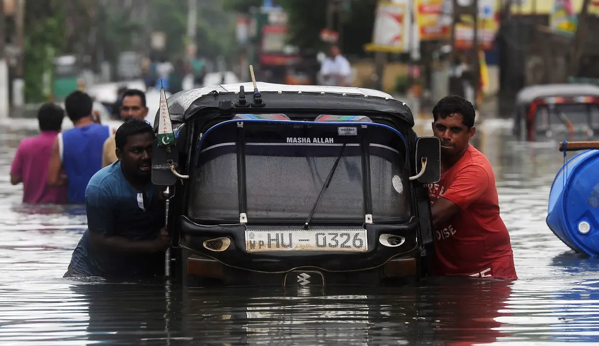 Warga mendorong bajaj saat banjir melanda kawasan mereka di Kaduwela, Kolombo, Sabtu (21/5/2016). Dikabarkan sekitar 80 orang tewas akibat hujan dan tanah longsor yang melanda Sri Lanka. (AFP Photo/Lakruwan W)
