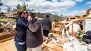 Seorang wanita memeluk keluarganya saat berada di puing-puing rumah mereka yang rusak usai diterjang badai di Elon, Virginia (16/4). Akibat badai ini sejumlah rumah rusak berat. (Jay Westcott/The News & Advance via AP)