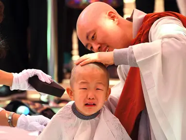 Seorang anak dicukur saat upacara berjudul 'Anak-anak Menjadi Buddha Monks', di kuil Jogye, Seoul, Rabu (19/4). Setelah upacara anak-anak akan tinggal di kuil selama dua minggu untuk mengikuti perayaan ulang tahun Buddha. (AFP PHOTO / JUNG Yeon-Je)