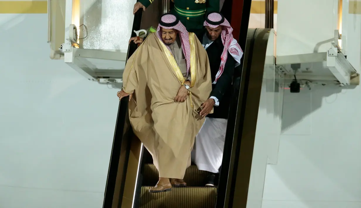 Raja Arab Saudi, Salman bin Abdulaziz Al Saud dibantu pengawalnya menuruni tangga eskalator saat tiba di Vnukovo International Airport, Rusia, 4 Oktober 2017. Ketika sang raja baru turun setengah tangga medadak eskalator emas itu mati (AP/Ivan Sekretarev)