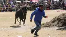 <p>Seorang matador amatir melarikan diri dari banteng selama Festival Our Lady of the Rosary di Desa Andes Huarina, Bolivia, Senin (3/10/2022). Sekelompok matador amatir melakukan parodi dari adu banteng Spanyol, tetapi tanpa mengorbankan banteng. (AP Photo/Juan Karita)</p>