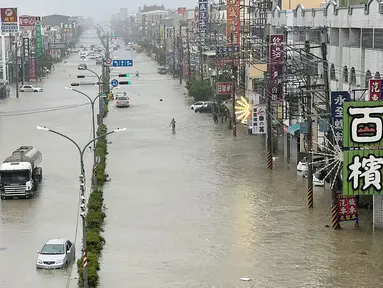 Orang-orang dan kendaraan menyeberangi air di sepanjang jalan yang tergenang banjir akibat Topan Gaemi di Kaohsiung, Taiwan pada tanggal 25 Juli 2024. ((Johnson LIU/AFP)