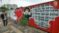 Pejalan kaki melintasi mural yang menghiasi tembok di kawasan Margonda, Depok, Sabtu (16/2). Gambar mural memiliki pesan agar masyarakat tetap damai dan berteman meski berbeda dalam memilih calon presiden dalam Pilpres 2019. (Liputan6.com/Herman Zakharia)