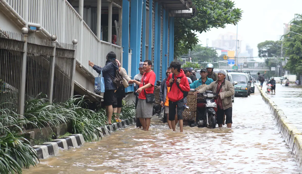 Warga melintasi genangan banjir di Jalan Gunung Sahari Jakarta, Selasa (25/2/2020). Hujan yang mengguyur Jakarta sejak Senin (24/2) malam membuat sejumlah kali meluap dan menyebabkan banjir. (Liputan6.com/Helmi Fithriansyah)