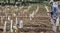 Petugas mendata makam pasien Covid-19 di TPU Bambu Apus, Jakarta, Selasa (2/3/2021). TPU Bambu Apus kini tidak lagi menampung pemakaman jenazah protokol Covid-19 akibat lahan di dua blok sudah penuh dan dialihkan ke TPU Srengseng Sawah. (merdeka.com/Iqbal S Nugroho)