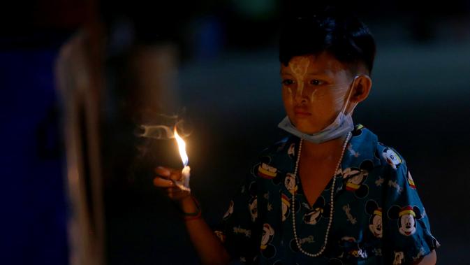 Seorang anak menyalakan lilin saat Festival Tazaungdaing di Yangon, Myanmar (29/11/2020). Festival itu dirayakan di Myanmar sebagai hari libur nasional dan menandai akhir musim hujan. (Xinhua/U Aung)