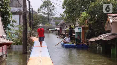 Warga berjalan melintasi jembatan apung saat banjir melanda Perumahan Periuk Damai, Tangerang, Banten, Selasa (23/2/2021). Adanya jembatan apung mempermudah warga saat melintasi banjir setinggi 2,5 meter di tempat tersebut. (Liputan6.com/Angga Yuniar)