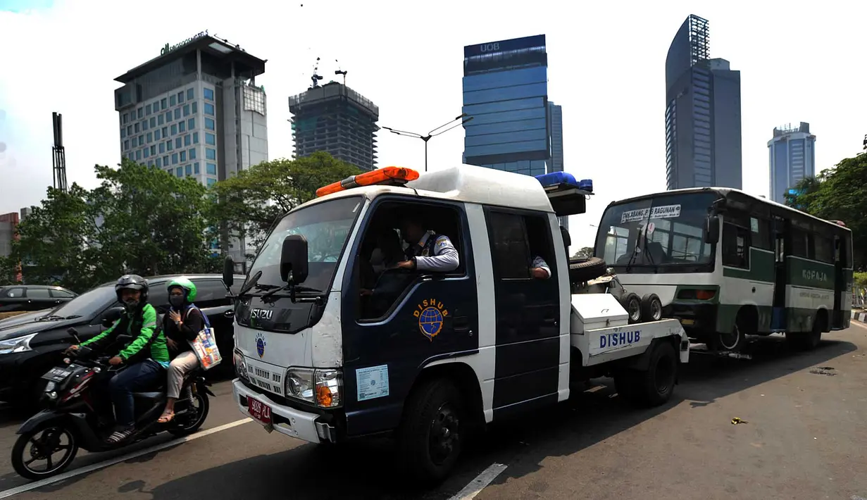Petugas Dinas Perhubungan (Dishub) DKI Jakarta menderek bus Kopaja yang ngetem di kawasan Stasiun Sudirman, Jakarta (17/7). Razia ini digelar untuk menyambut Asian Games Agustus mendatang. (Merdeka.com/Arie Basuki)