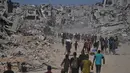 Pengungsi Palestina berjalan melewati bangunan-bangunan yang hancur saat mereka kembali ke rumah mereka di kawasan Zeitoun, Kota Gaza, pada Jumat 10 Oktober 2025, setelah Israel dan Hamas sepakat untuk menghentikan sementara perang mereka dan membebaskan sandera yang tersisa. (AP Photo/Jehad Alshrafi)
