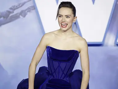 Aktris Inggris Daisy Ridley tertawa di karpet merah saat tiba menghadiri pemutaran perdana film Star Wars: The Rise Of Skywalker" di London (18/12/2019). Daisy Ridley tampil anggun dengan memancarkan kemewahan dalam balutan gaun navy ball straples. (AFP/Tolga Akmen)