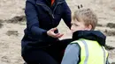 Kate Middleton, Duchess of Cambridge, tersenyum saat membersihkan sampah yang berserakan bersama anak-anak sekolah di pantai Newborough di Wales (8/5). (Reuters/Phil Noble)