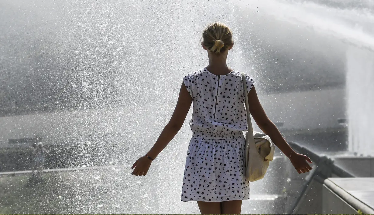 Seorang wanita menikmati air mancur di sebuah kolam di Trocadero Fountains, Paris (22/7/2019). Warga Paris bersiap menghadapi suhu terpanas pada minggu ini ketika gelombang panas akan melanda ke Eropa utara. (AFP Photo/Alain Jocard)