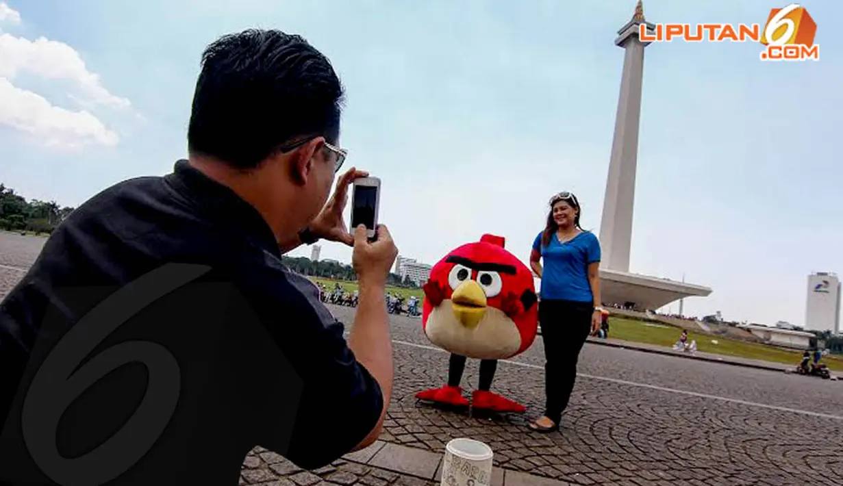 Seorang wanita tampak berpose dengan badut boneka Angry Bird yang sengaja   mangkal untuk menghibur pengunjung (Liputan6.com/Faizal Fanani)