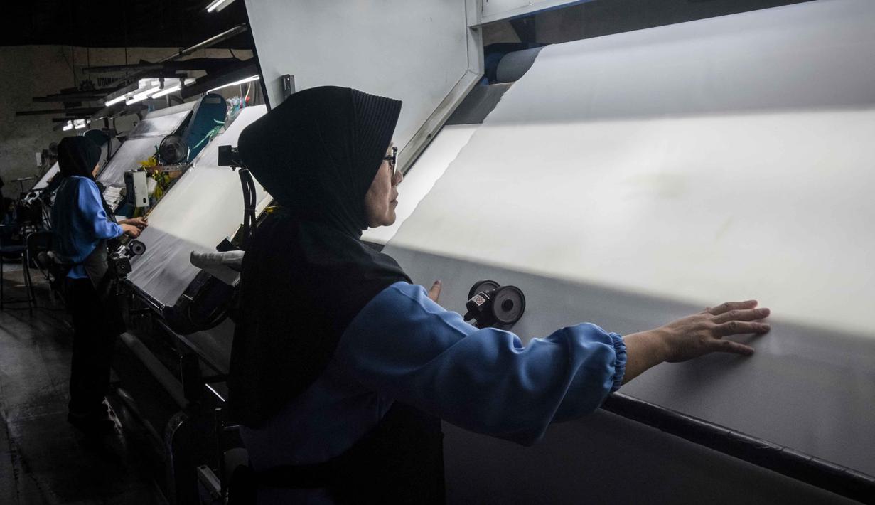 Lonjakan harga bahan baku didorong oleh kenaikan harga minyak mentah dunia, yang memengaruhi biaya bahan baku berbasis petrokimia (seperti polyester) dan biaya logistik. Situasi ini menyebabkan efek domino yang signifikan terhadap industri hilir, termasuk plastik dan kemasan, dengan kenaikan biaya produksi yang mencapai 90–100 persen. Tampak dalam foto, para pekerja memeriksa kain di Trisula Textile Industries, Cimahi, Jawa Barat pada Rabu 22 April 2026, saat para produsen tekstil menghadapi biaya yang lebih tinggi akibat melonjaknya harga bahan baku petrokimia yang terkait dengan kenaikan harga minyak global. (Timur MATAHARI/AFP)