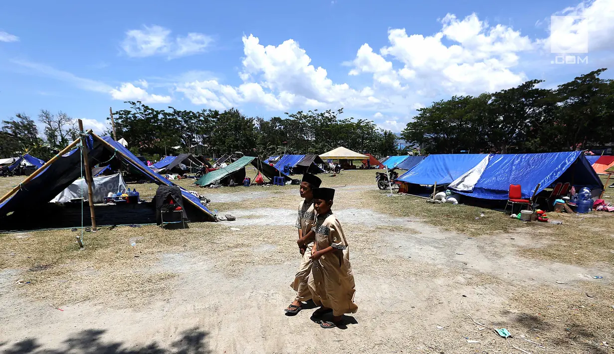 Anak-anak pengungsi berjalan di kamp pengungsian di Lapangan Masjid Agung Daru Salam, Palu, Jumat (5/10). Para pengungsi menggelar salat jumat pertama pascagempa bumi dan tsunami. (Liputan6.com/Fery Pradolo)