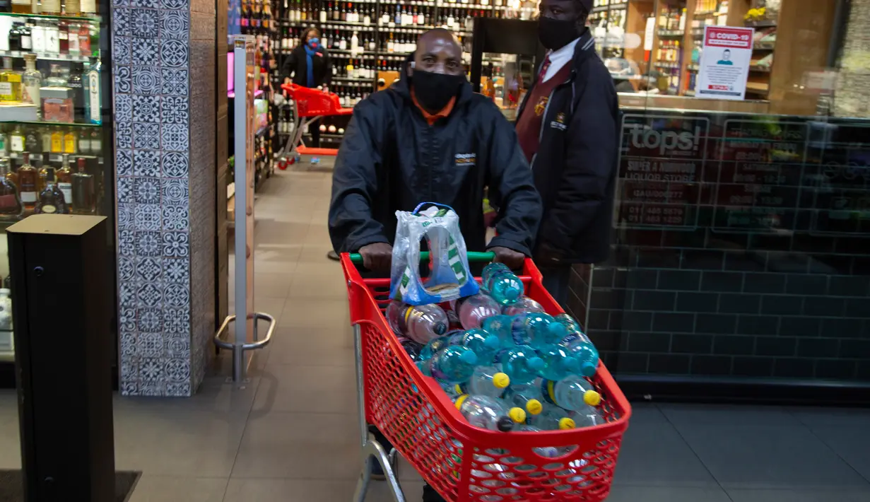 Pelanggan meninggalkan toko minuman keras dengan belanjaannya ketika Afrika Selatan mencabut larangan penjualan alkohol dan rokok di Johannesburg, Selasa (18/8/2020). Pembelian alkohol dan rokok dilarang ketika Afrika Selatan memberlakukan lockdown ketat pada 27 Maret 2020. (AP Photo/Denis Farrell)