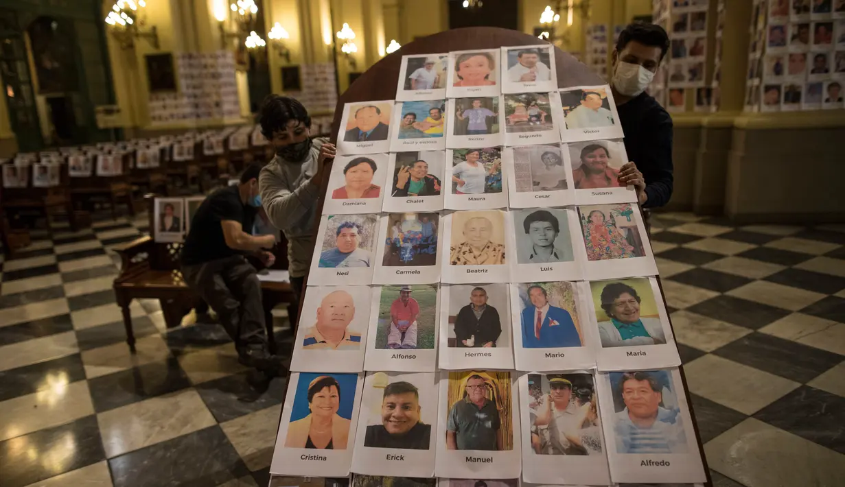 Pekerja memegang panel kayu setelah menempelinya dengan potret korban meninggal akibat virus corona di dalam Katedral, di Lima, Peru pada 13 Juni 2020. Misa Minggu di Katedral Lima dihadiri lebih dari 4.000 potret mereka yang telah meninggal dalam pandemi Covid-19 yang menyebar di Peru. (AP Photo/Ro