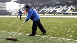 Ground staff try to clear ice from the pitch before Fulham's Premier League match against Blackburn at Craven Cottage, London, on January 10, 2009. AFP PHOTO / Glyn Kirk