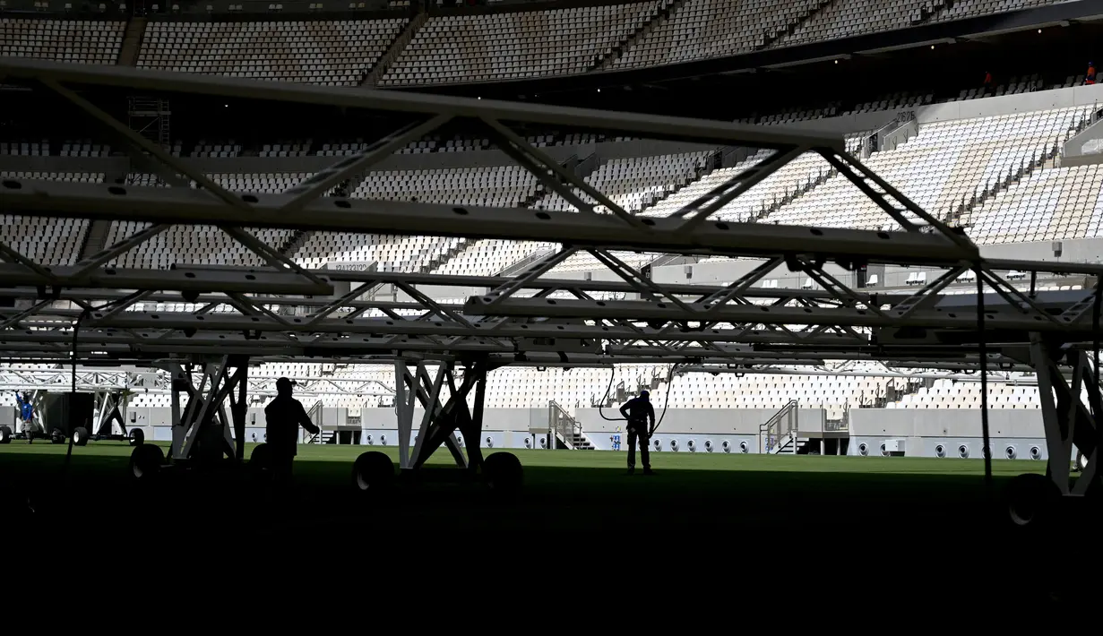 Para pria bekerja di lapangan Lusail Stadium, Lusail, Qatar, 28 Maret 2022. Stadion berkapasitas 80 ribu penonton yang terletak di pinggiran Ibu Kota Doha ini akan menjadi tuan rumah final Piala Dunia 2022 pada bulan Desember mendatang. (GABRIEL BOUYS/AFP)