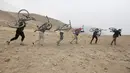 Sejumlah pemuda Afghanistan mengangkat sepedanya menaiki bukit saat berlatih Dirt Jump (DJ) di Kabul, Afghanistan (20/11). Sepeda Dirt Jump memiliki setang yang mirip dengan BMX tetapi frame lebih besar. (Reuters/Omar Sobhani)