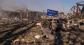 Pemandangan sebuah mobil yang hancur di tengah bangunan-bangunan yang rusak, serta rambu jalan yang menunjukkan arah dan jarak ke Kyiv dan Zhytomyr, setelah serangan Rusia menghantam sebuah gudang yang kemudian disusul oleh ledakan di desa Myla, wilayah Kyiv, Ukraina, Sabtu, 29 Agustus 2026. (Foto AP/Dan Bashakov)