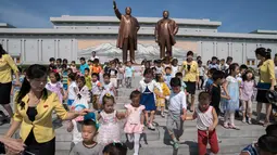 Anak-anak berjalan di depan patung pemimpin Korea Utara Kim Il Sung (kiri) dan Kim Jong Il (kanan), setelah meletakkan bunga untuk menandai peringatan 24 tahun kematian Kim Il Sung, di bukit Mansu, Pyongyang, Minggu (8/7). (AP Photo/Andrew Harnik, Pool)