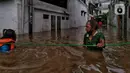 Warga berpegangan pada tali saat berjalan menyusuri banjir yang merendam permukiman di kawasan Kebalen, Jakarta, Sabtu (20/2/2021). Curah hujan yang tinggi menyebabkan banjir setinggi orang dewasa di kawasan Kebalen. (Liputan6.com/Johan Tallo)