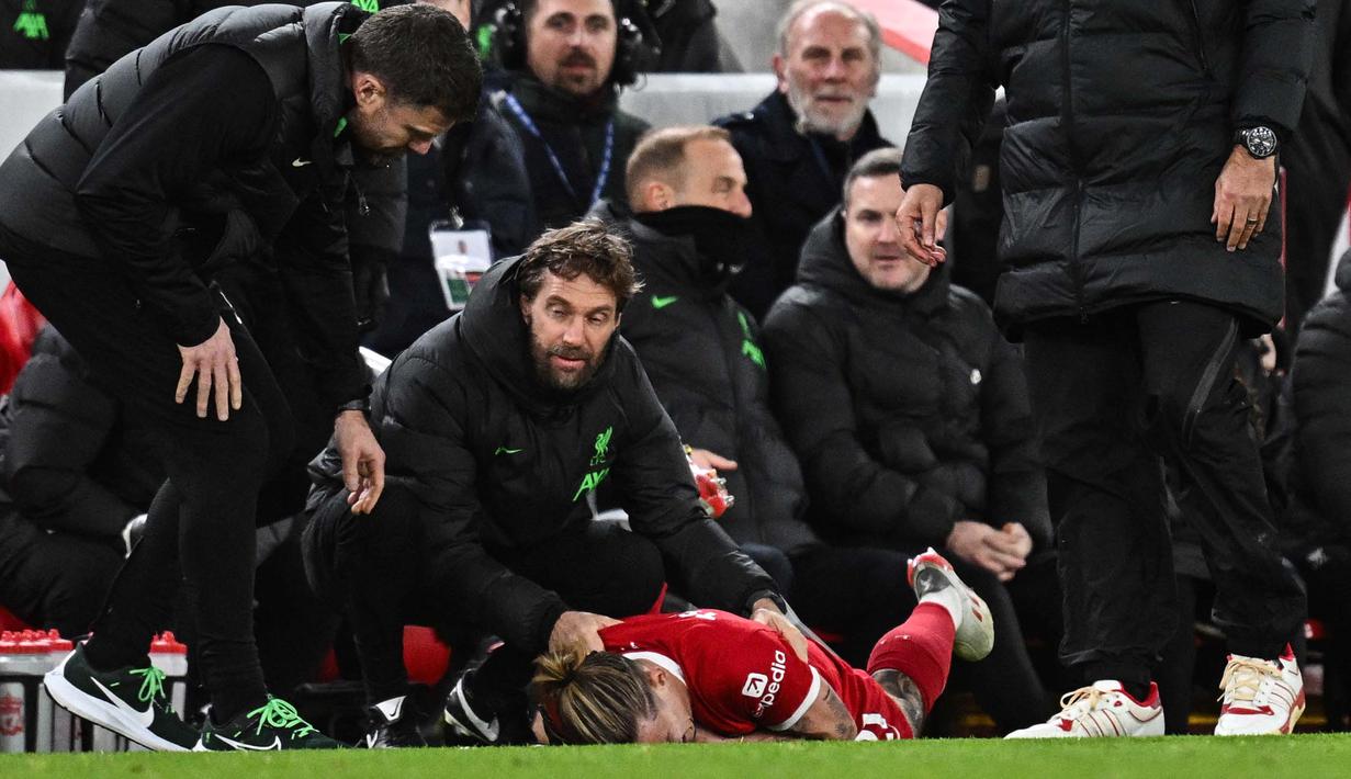 Pemain Liverpool, Kostas Tsimikas, terkapar setelah berduel dengan pemain Arsenal, Bukayo Saka pada laga pekan ke-18 Premier League 2023/2024 di Stadion Anfield, Minggu (24/12/2023). (AFP/Paul Ellis)