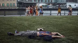 Seorang pria beristirahat di taman saat senja selama gelombang panas musim panas di Hoboken, NJ, Kamis (21/7/2022). Gelombang panas bisa berlanjut selama berhari-hari dan membuat suhu melonjak di tempat-tempat seperti Boston, Little Rock, dan Pantai Virginia. (AP Photo/Andres Kudacki)